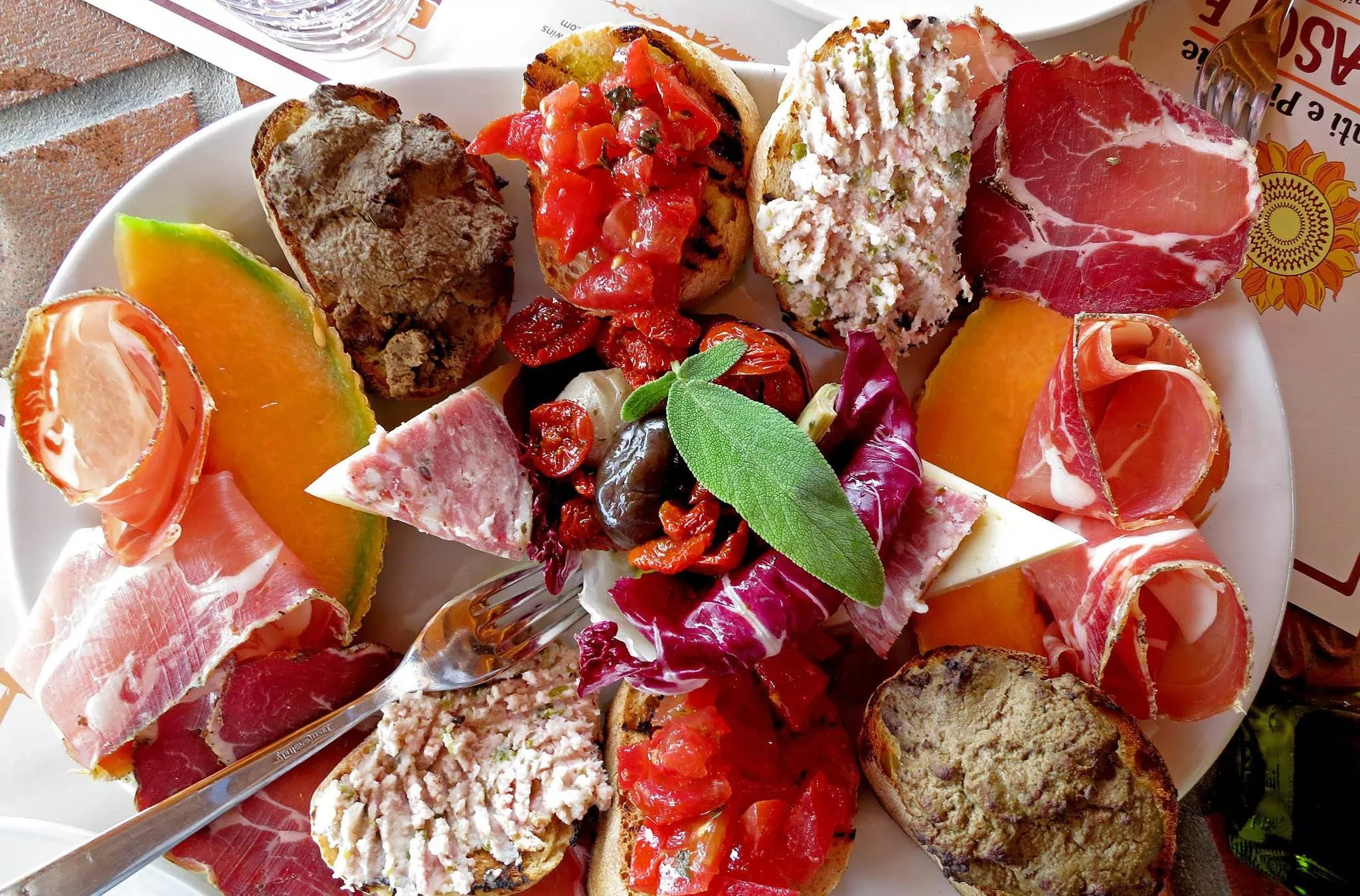 Macht Lust auf mehr: ein toskanischer Vorspeisenteller mit verschiedenen Crostini, eingelegten Tomaten und Schinken
