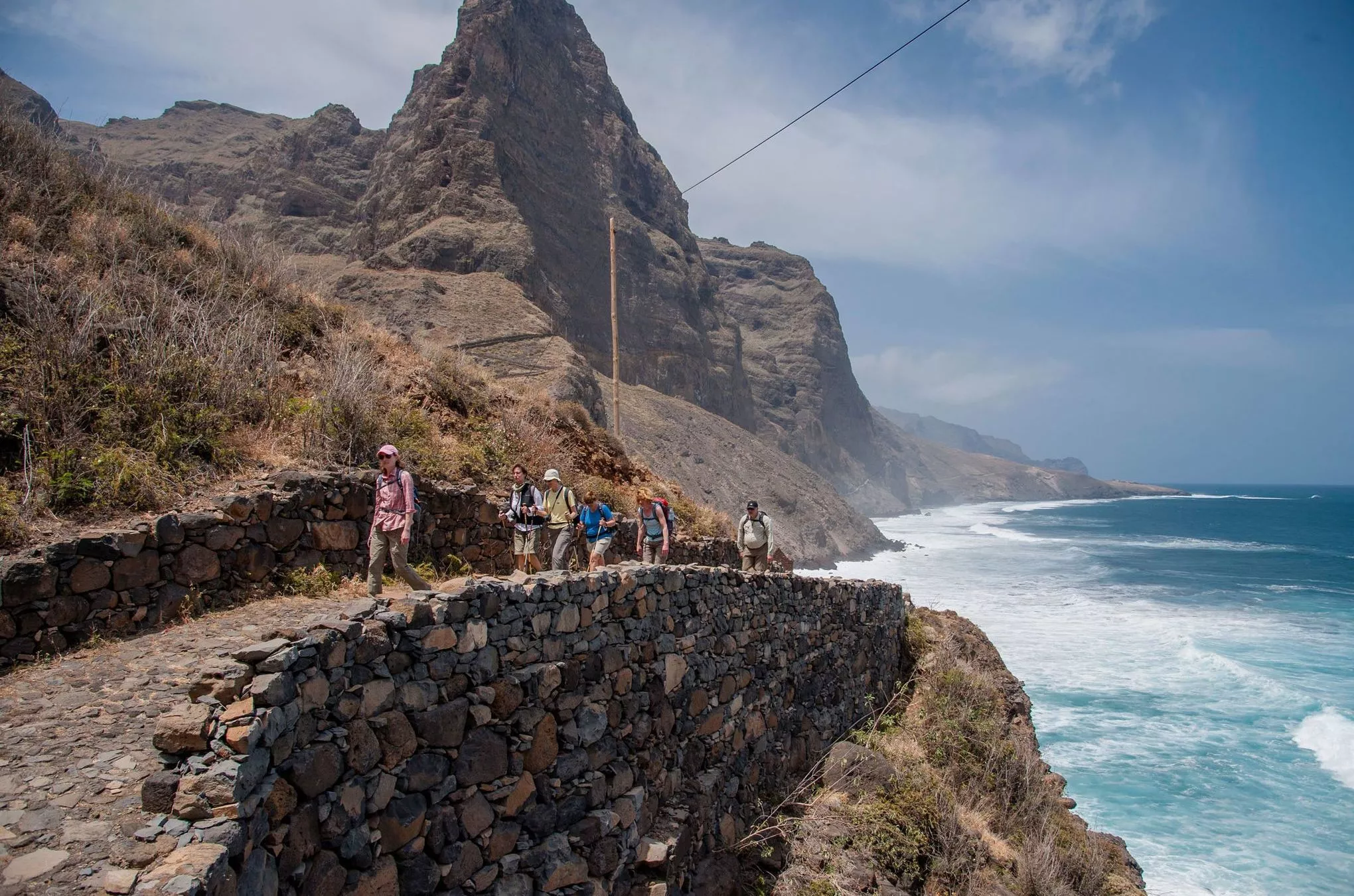Zwischen hohen Felswänden und dem offenen Meer erklimmen die Wanderer uralte Wege entlang der Küste