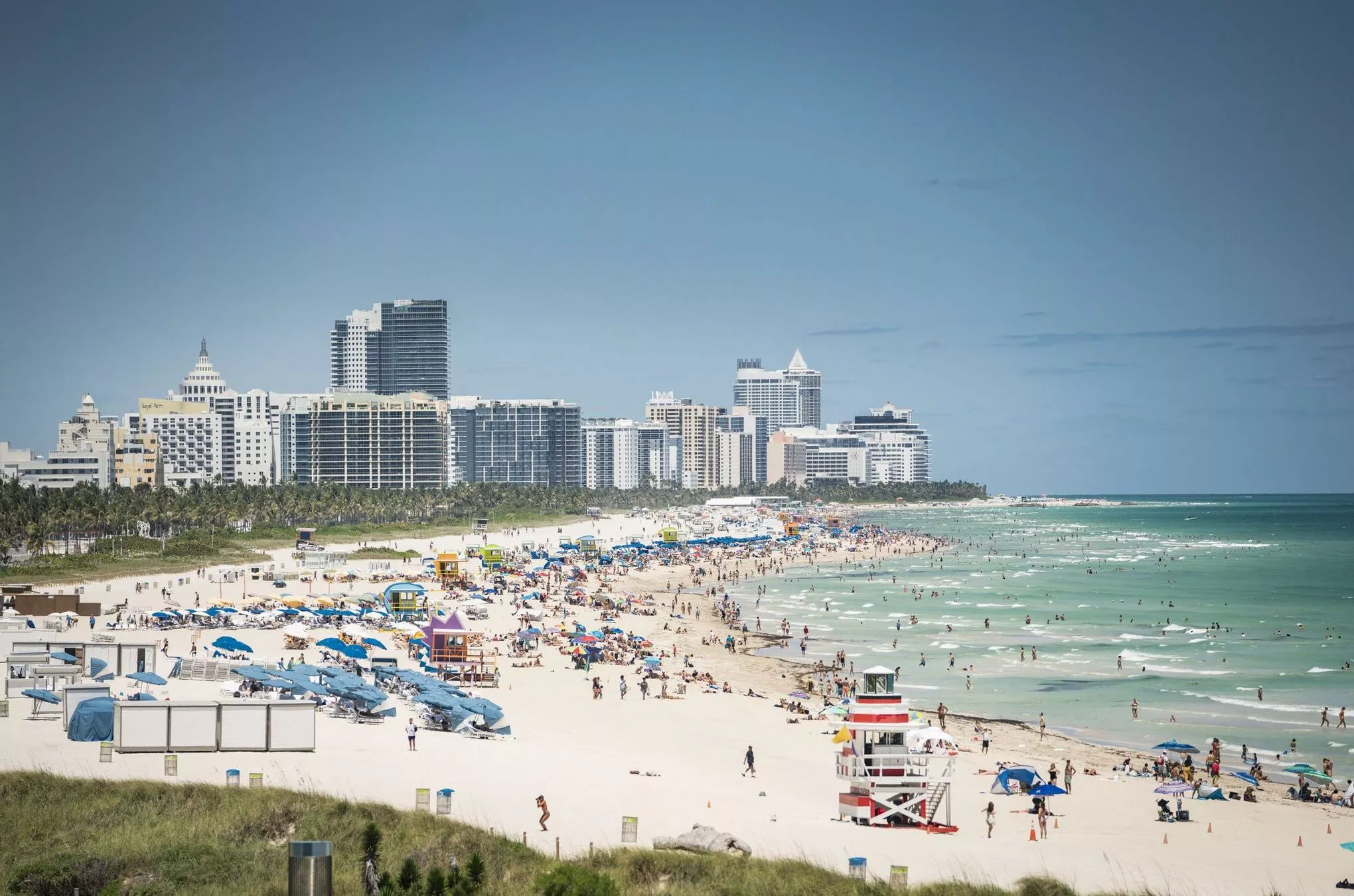 Vorne der lange weiße Sandstrand von Miami Beach, im Hintergrund ragen die modernen Wohntürme mit garantiertem Ozeanblick in den Himmel