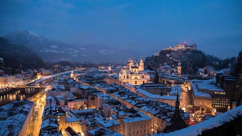 Salzburg bei Dämmerung im Schnee: Dom, Barockviertel, Festung Hohensalzburg auf dem Hügel, Salzach durch verschneite Stadt.