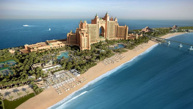 Luftaufnahme des Atlantis The Palm Resorts in Dubai: Sandstrand, Pools, Palmen, Brücke zum Meer und prunkvolles Palastgebäude.