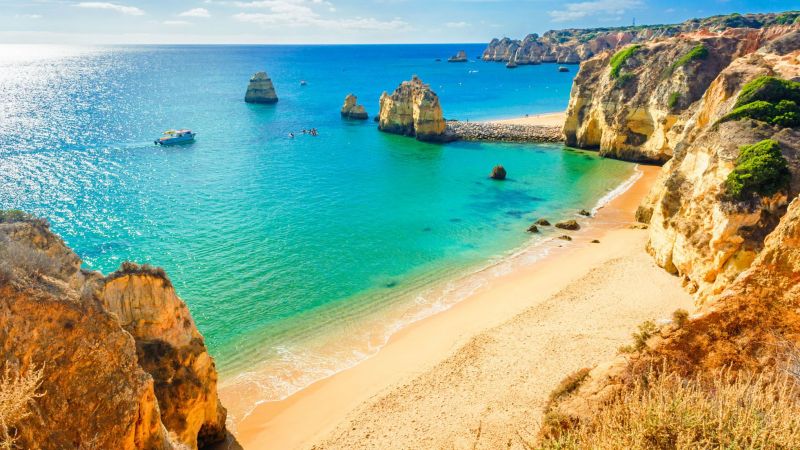 Türkises Wasser, goldener Sand und Felsklippen der Algarve nahe Lagos; Boote in der Bucht vor steilen Klippen. Türkises Wasser, goldener Sand und Felsklippen der Algarve nahe Lagos; Boote in der Bucht vor steilen Klippen.