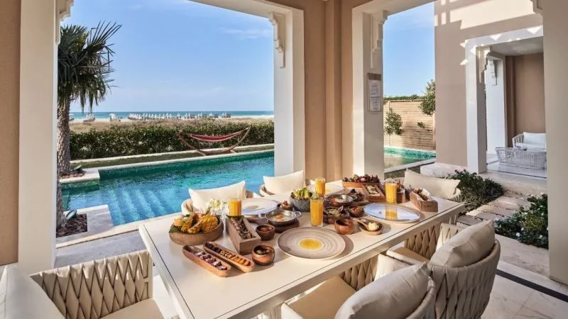 Balkon der Superior Villa am Club Privé: Frühstückstafel mit Speisen, Blick auf Pool, Strand und Meer.