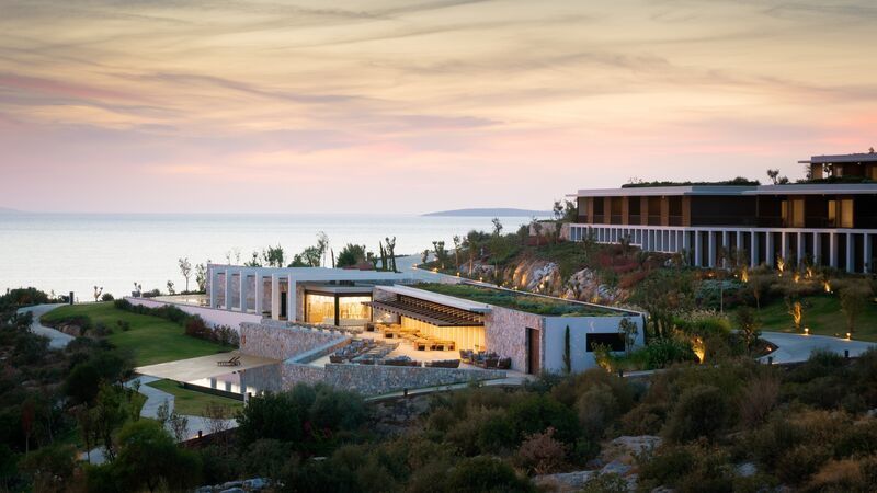 Außenansicht des Haupthauses von Six Senses Kaplankaya bei Sonnenuntergang über dem Meer.