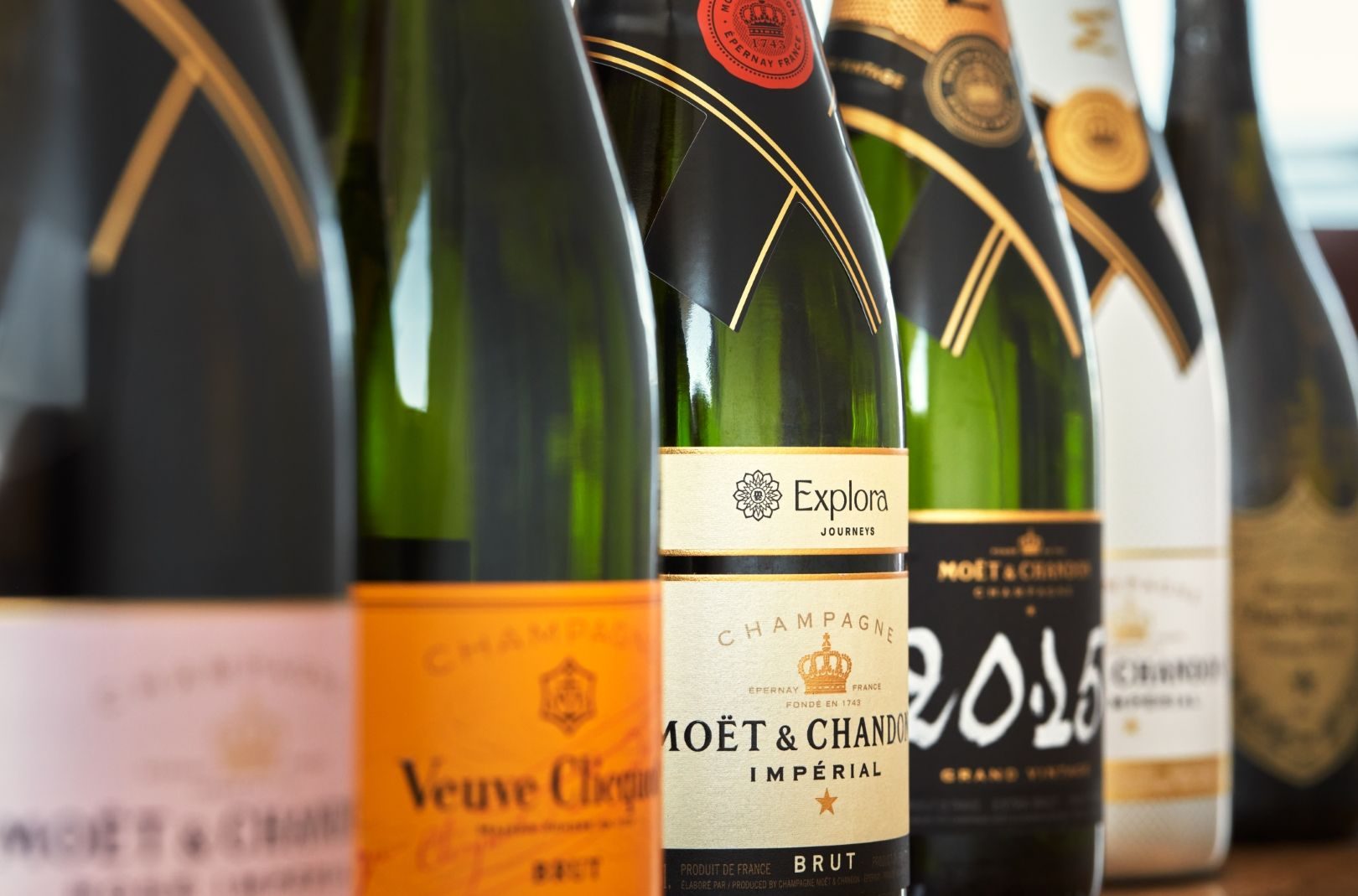Nahaufnahme mehrerer Champagnerflaschen im Regal, zentrales Etikett mit Explora Journeys und Moët & Chandon Imperial
