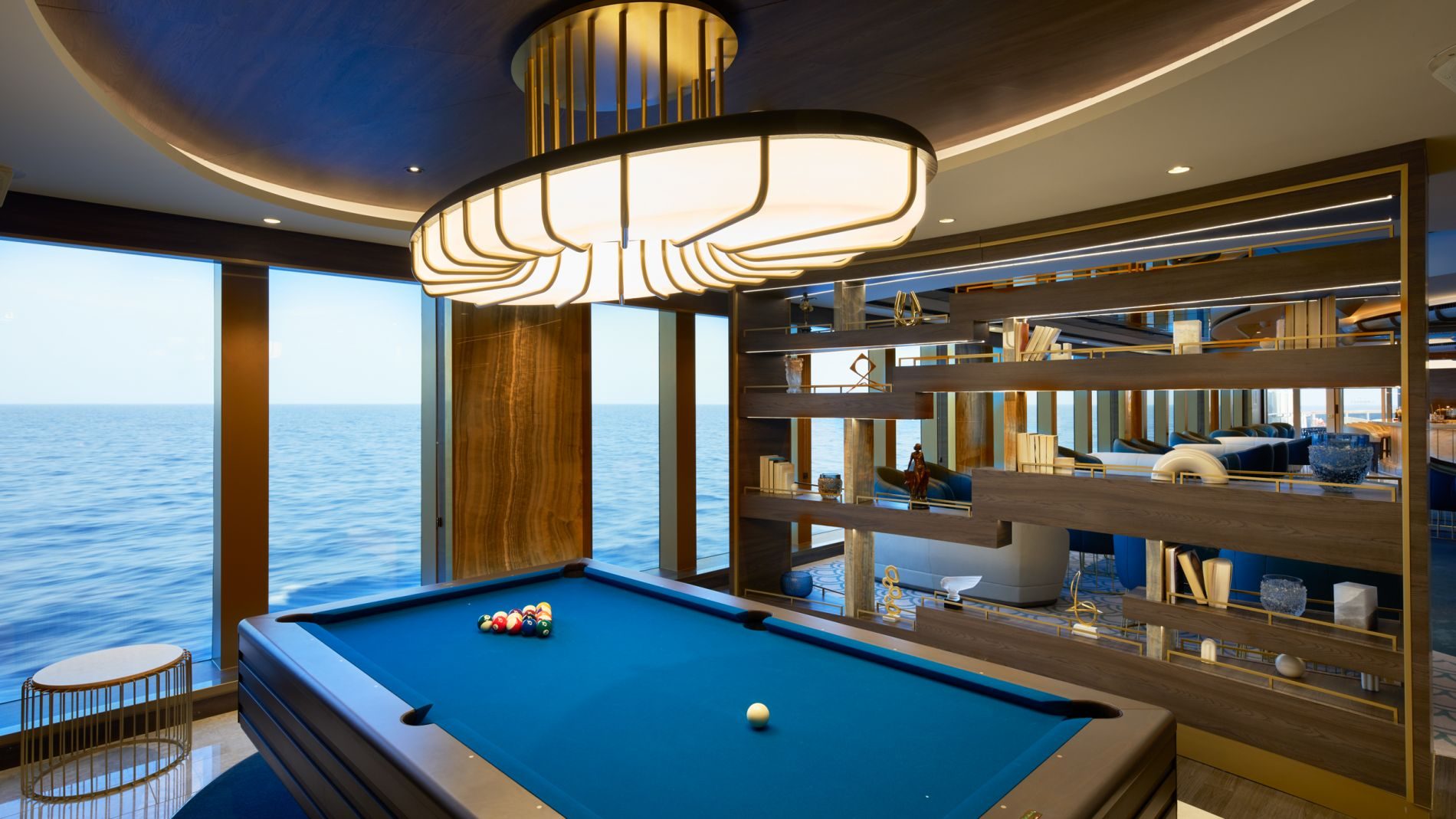 Billardtisch im Innenbereich mit Meerblick, moderne helle Leuchte, Holzregal-Trennwand und Loungebereich.