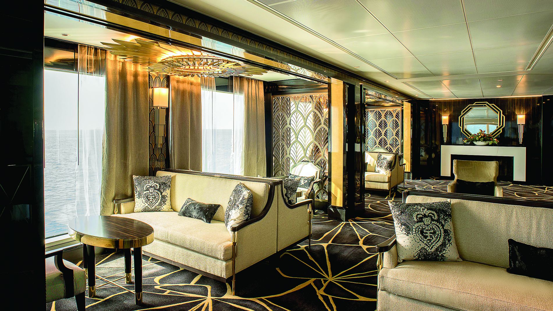 Luxus-Lounge an Bord von Regent Seven Seas mit Meerblick, beige Sofas, dekorative Kissen, goldene Akzente, geometrischer Teppich Luxus-Lounge an Bord von Regent Seven Seas mit Meerblick, beige Sofas, dekorative Kissen, goldene Akzente, geometrischer Teppich