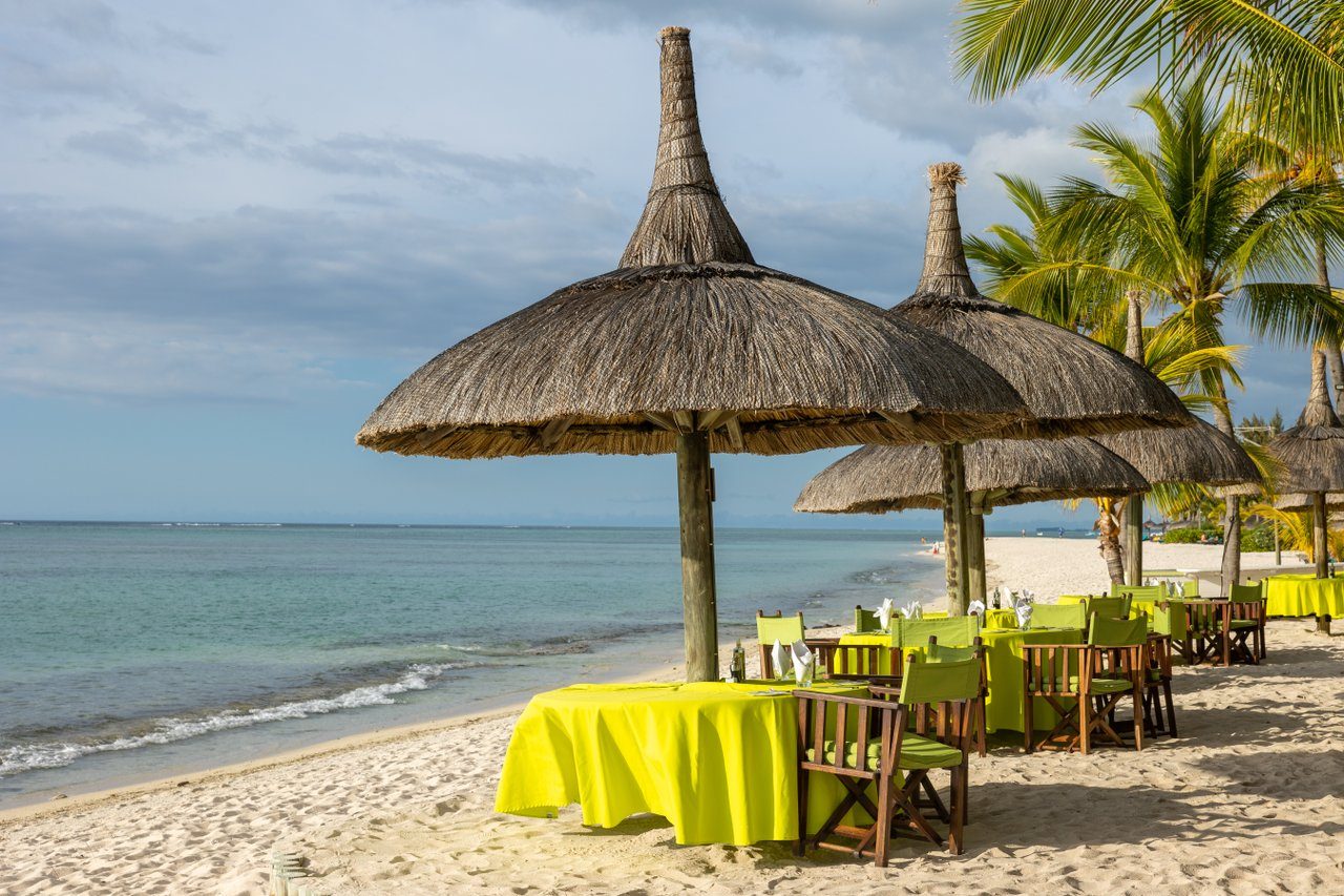 Strandrestaurant La Plage am Dinarobin Resort: Strohdachschirme, gelbe Tische, Stühle am Sandstrand mit Meerblick. Strandrestaurant La Plage am Dinarobin Resort: Strohdachschirme, gelbe Tische, Stühle am Sandstrand mit Meerblick.