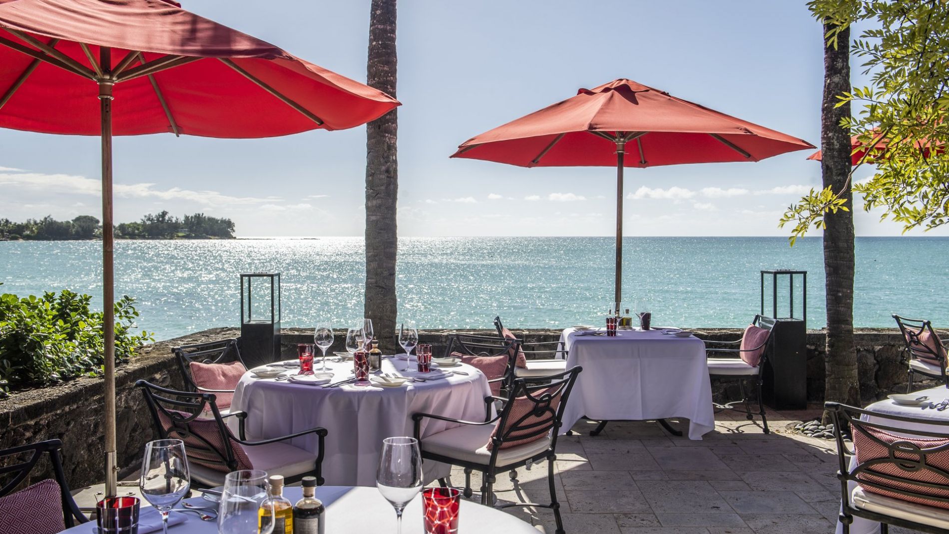 Außerhalb am Strand: Tische mit weißen Tischtüchern, rote Sonnenschirme, Blick aufs Meer am Beachcomber Resort. Außerhalb am Strand: Tische mit weißen Tischtüchern, rote Sonnenschirme, Blick aufs Meer am Beachcomber Resort.