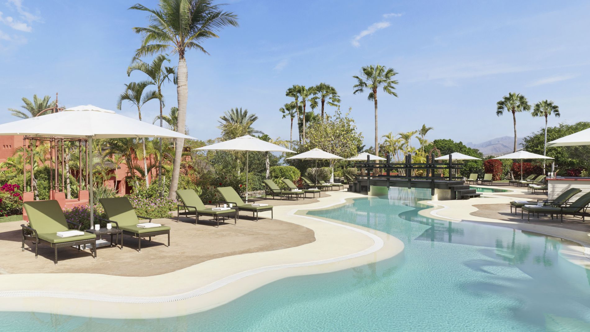 Ritz-Carlton Tenerife Abama Villa Pool: Liegen unter Sonnenschirmen, Palmen, Brücke, türkisblaues Wasser.