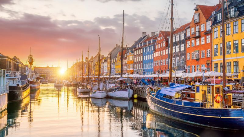Kopenhagen Nyhavn Hafen bei Sonnenuntergang; bunte Häuserzeilen, Segelboote am Wasserkanal, ruhige Spiegelung. Kopenhagen Nyhavn Hafen bei Sonnenuntergang; bunte Häuserzeilen, Segelboote am Wasserkanal, ruhige Spiegelung.