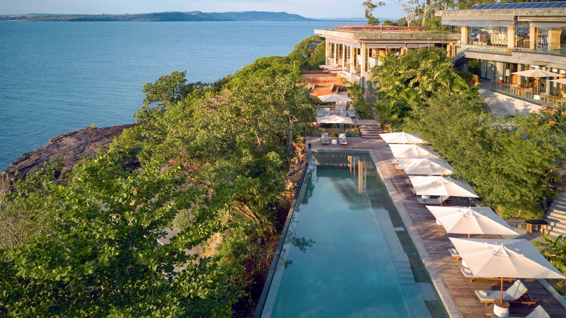Luftaufnahme des Hauptpools auf Krabey Island, umgeben von Liegen, Sonnenschirmen und Resort-Gebäuden am Meer.
