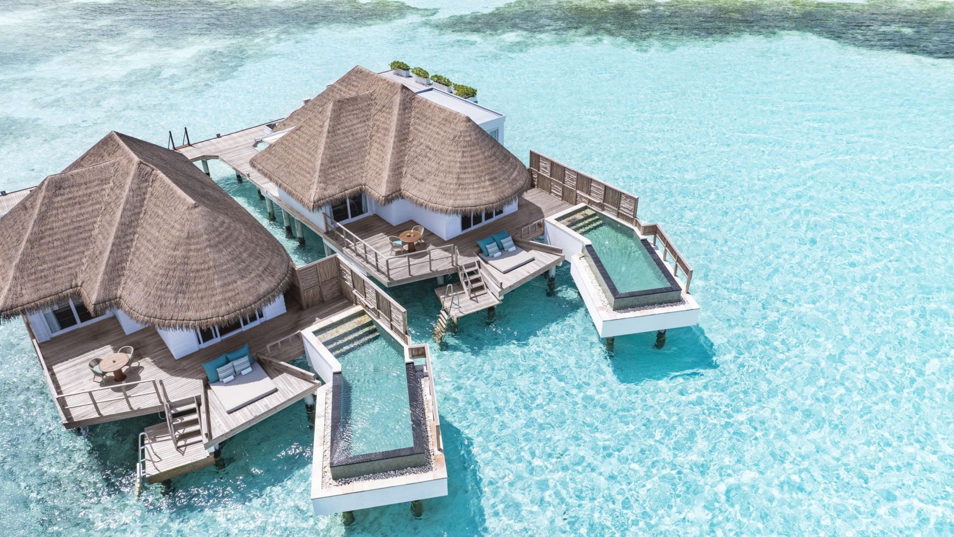 Kanuhura Over-Water Villen mit Strohdach, Holzdecks und Terrassenpools über türkisblauem Meer; Six Senses.