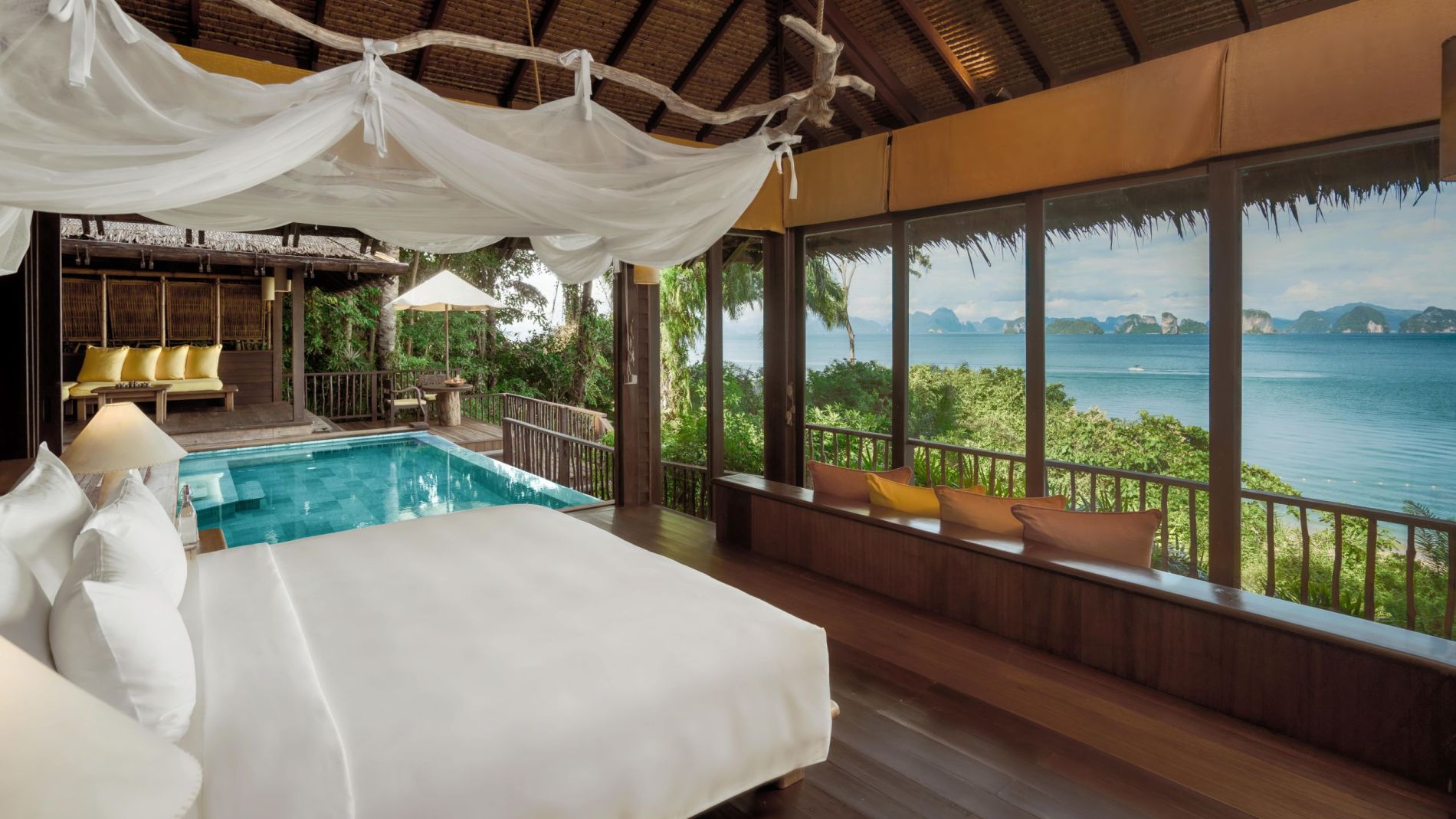 Strandvilla-Bettzimmer mit weißer Bettwäsche, luftigen Stoffbahnen, privatem Pool und Meerblick auf Inseln.