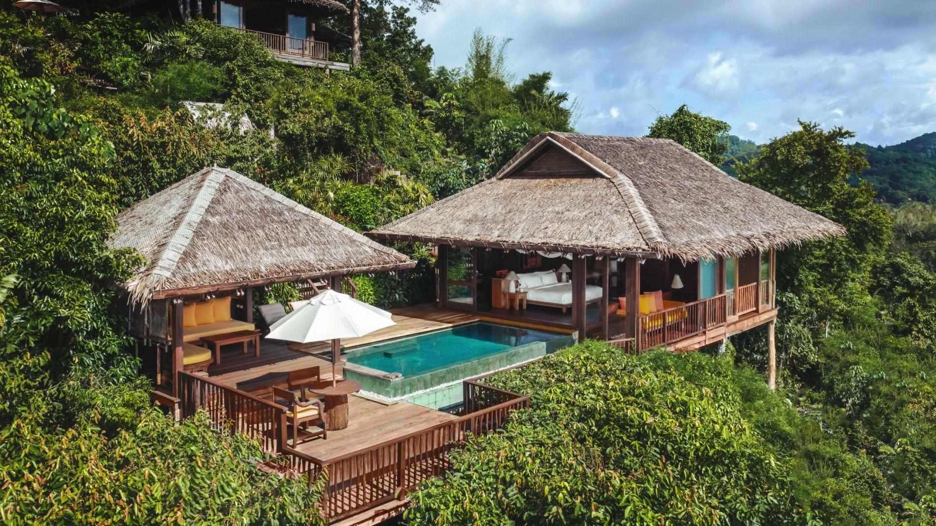 Luxuriöse Villa mit Strohdach am Berghang, Terrasse mit Pool und Lounge, umgeben von grünem Dschungel (Six Senses Yao Noi).