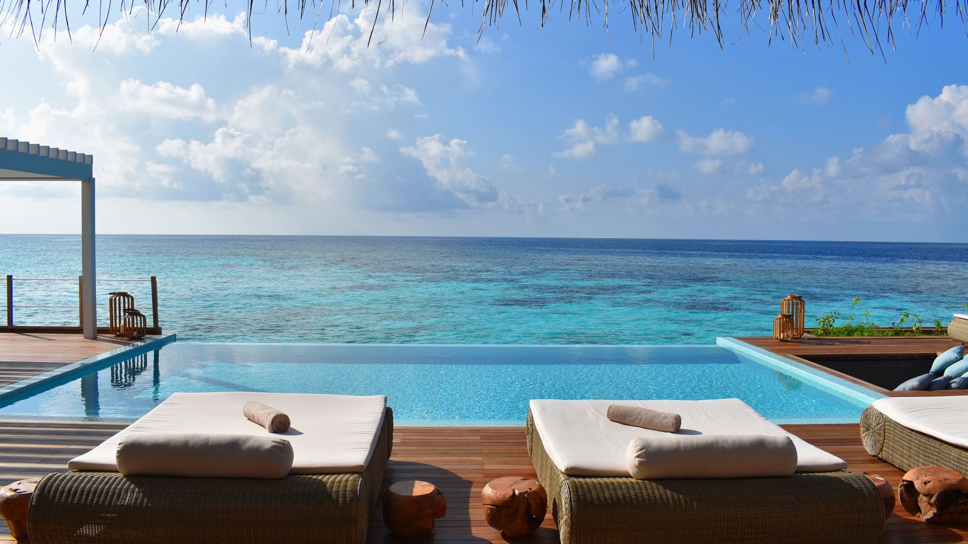 Lounge-Betten am Rand eines Infinity-Pools mit Meerblick und blauem Himmel im Baglioni Resort Maldives.