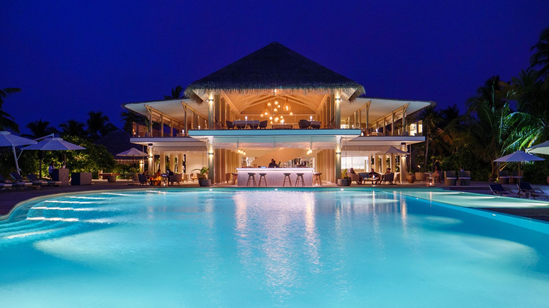 Nächtlicher Poolblick auf das zweistöckige Open-Air-Restaurantbar mit Palapa-Dach im La Limonaia, Baglioni Maldives