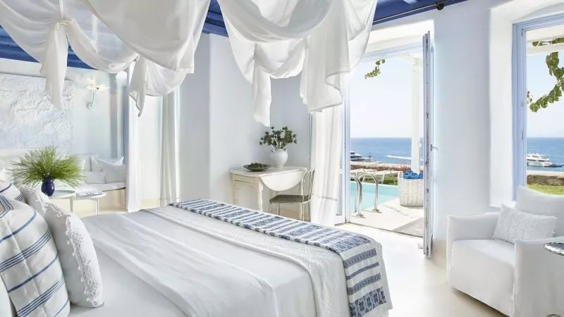 Helles, elegantes Zimmer mit Meerblick, weißen Wänden, blauen Decken und stilvollen Möbeln.