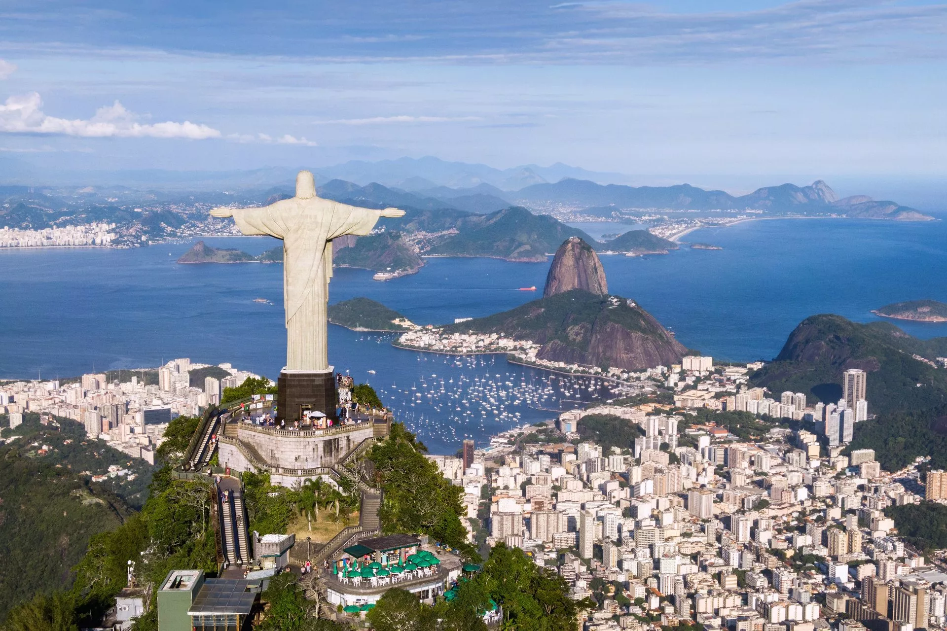 Luftaufnahme des Christus-Erlösers mit dem Zuckerhut und der Stadt Rio de Janeiro im Hintergrund.